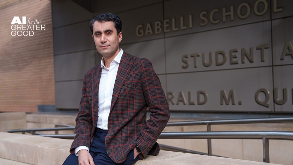 A Fordham Focus on AI: Why Humans Still Make the Best Co-Workers A man wearing a suit and a dress shirt sits on a concrete wall with one hand in his pocket