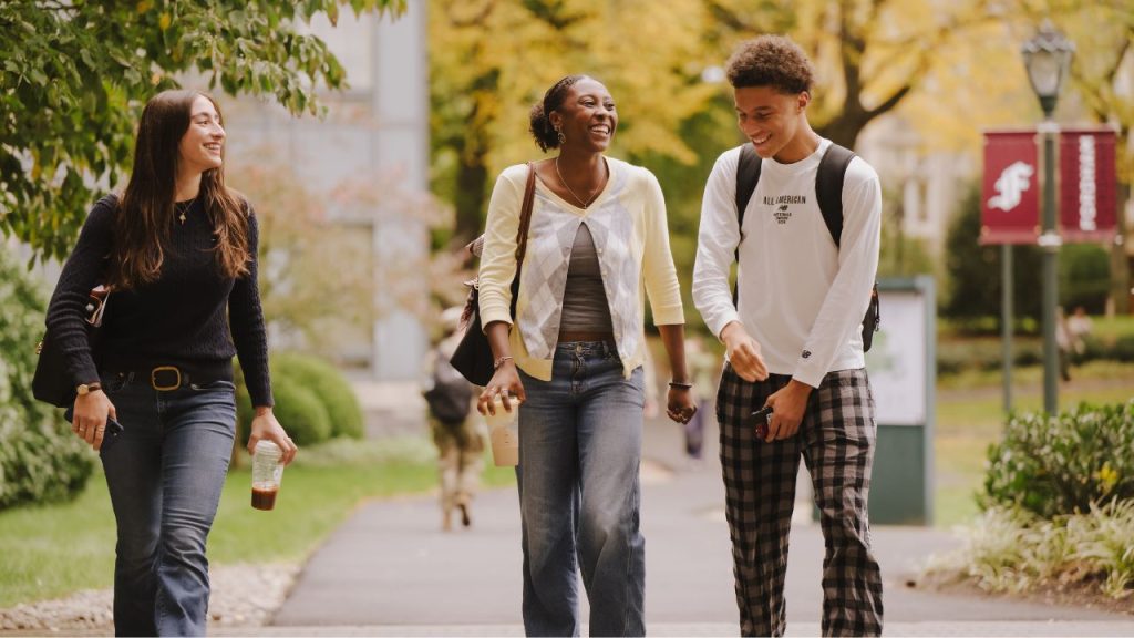 Three Fordham students laugh while walking across campus representing the Jesuit Educated campaign