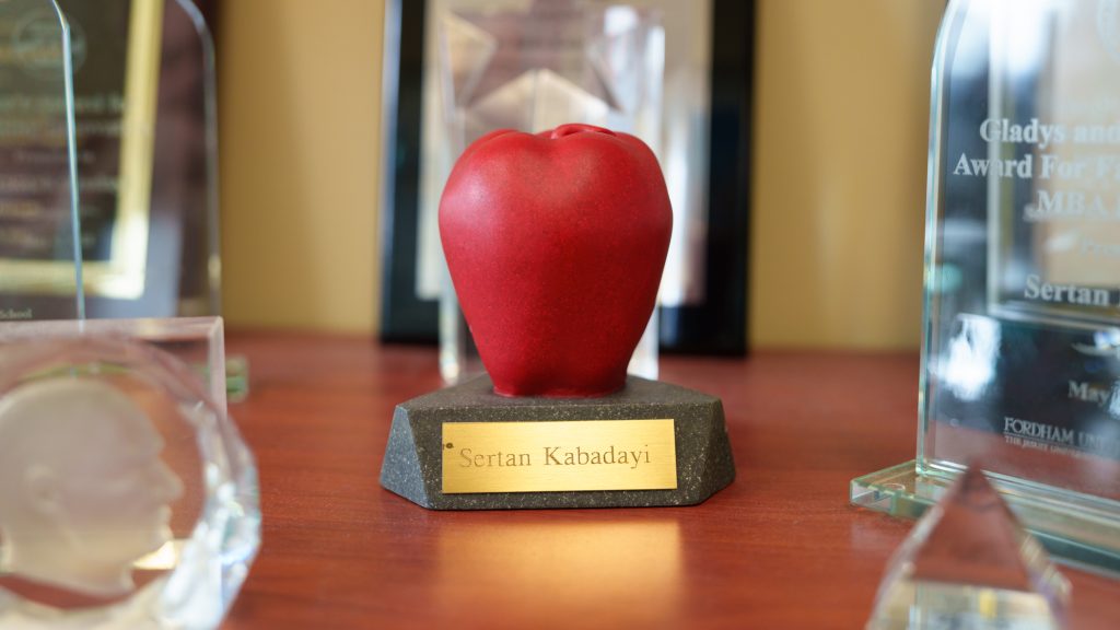 A fake apple with the name "Sertan Kabadayi" engraved below