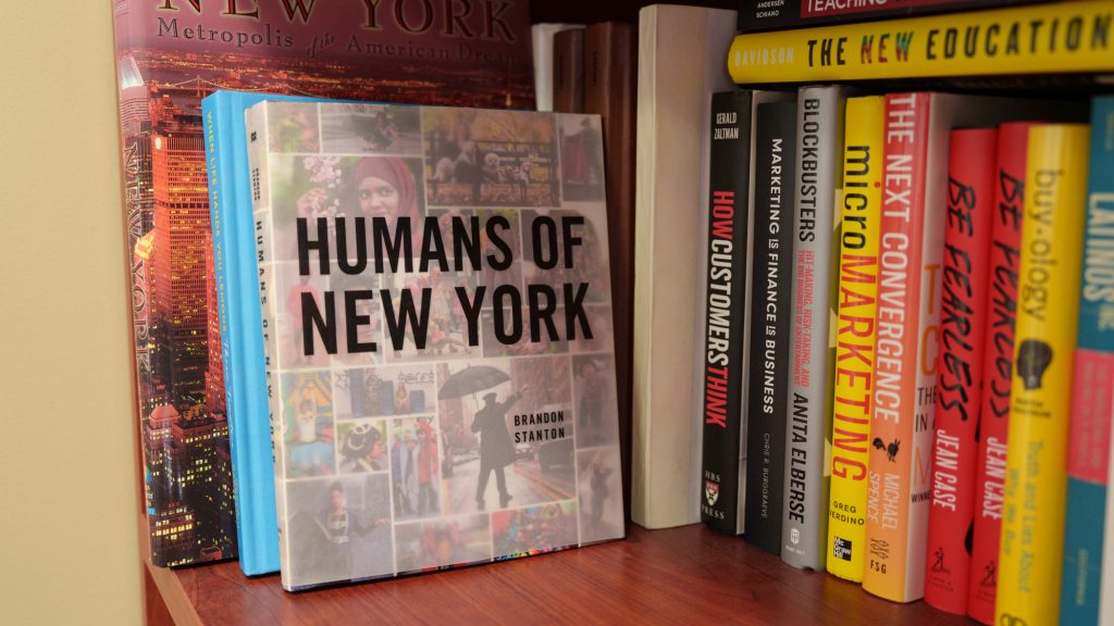 The book "Humans of New York" surrounded by books on a bookshelf