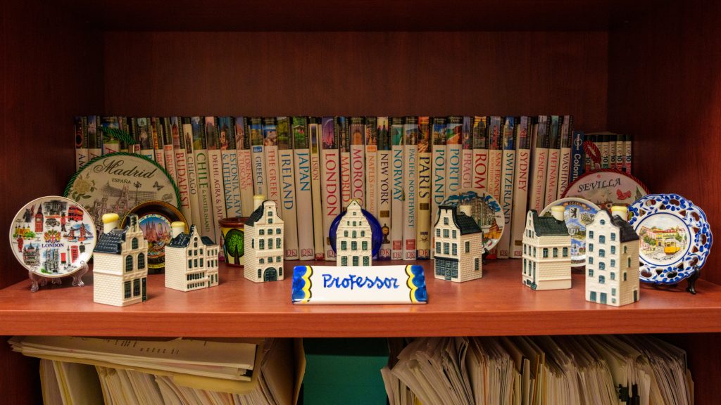 A collection of books and art souvenirs from around the world on a bookshelf