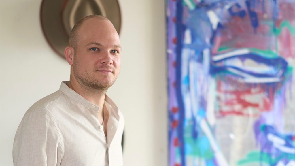 Oliver Barnett posing in front of a colorful painting