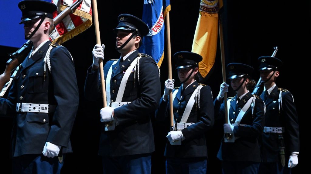 ROTC in uniform holding colorful flags