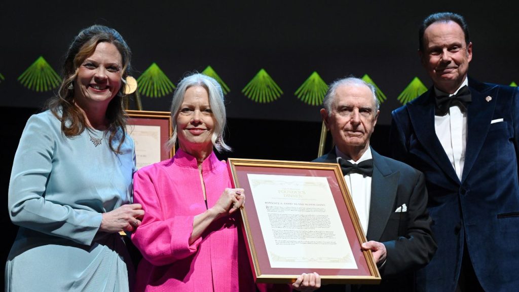 couple holding award flanked by president and board chair