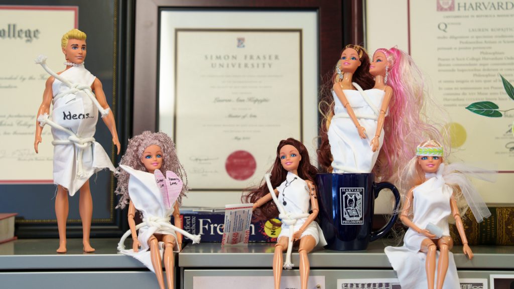 Six Barbie dolls on a desk