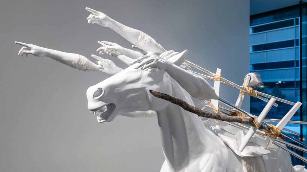 A photo of a sculpture of a white horse with human hands, part of the Whitney Biennial exhibition. 