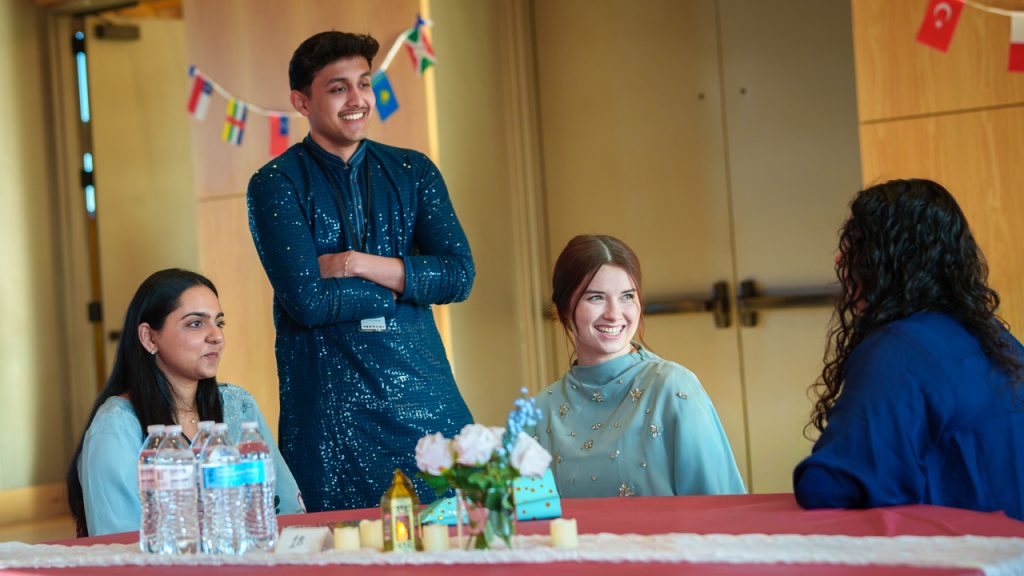 Four students sitting together at a table and chatting