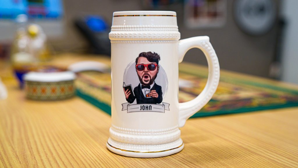 A white mug with a cartoon version of John Gownley in a suit