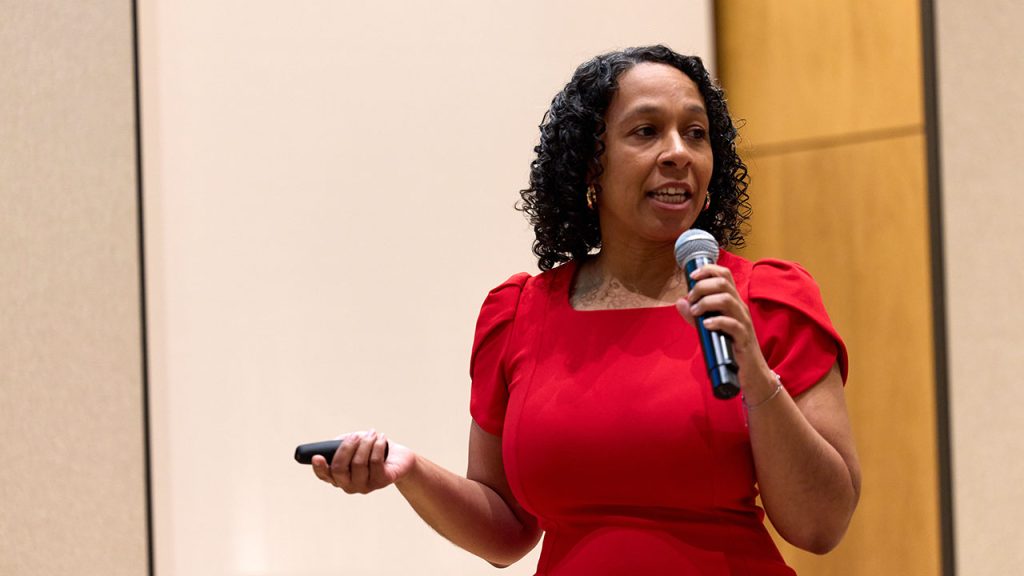 A woman wearing red speaks into a microphone.