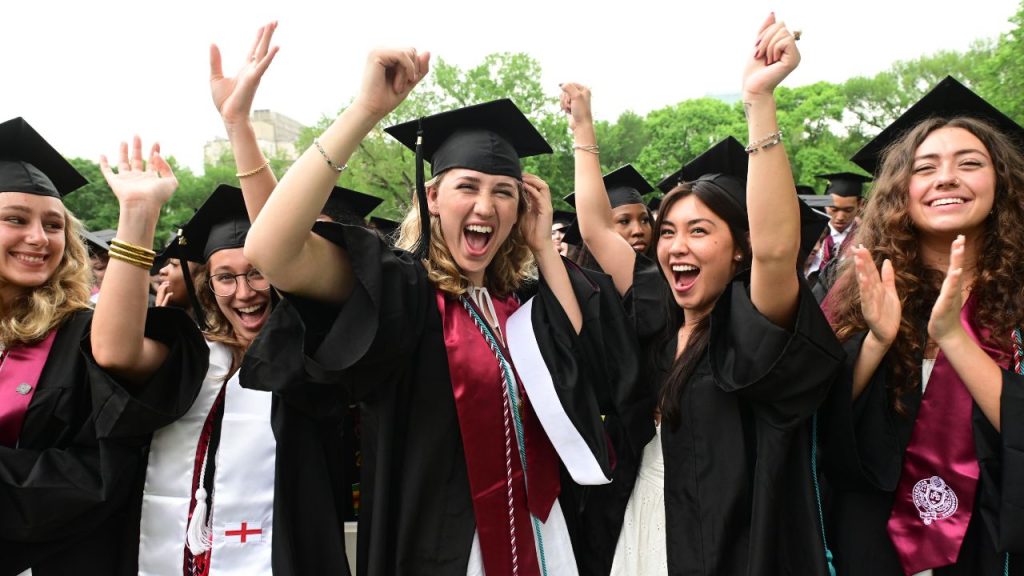 A group of graduates cheering in cap and gown