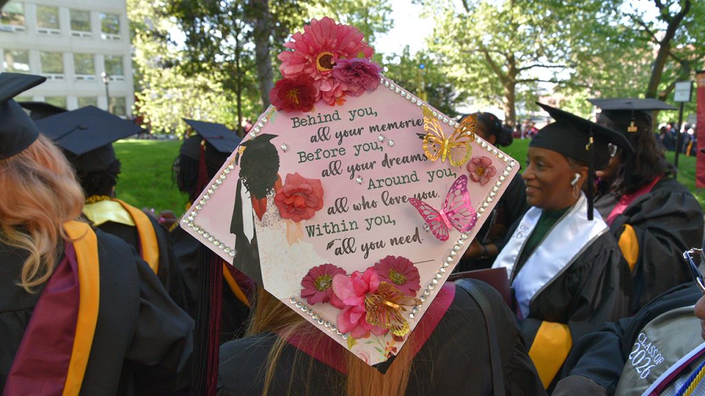 Commencement cap that says "Behind you, all your memories; Before you, all your dreams; Around you, all who love you; Within you, all you need"
