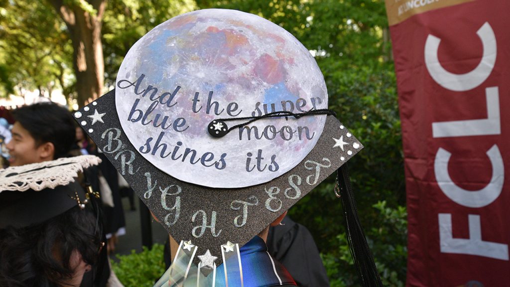 Commencement cap that says "And the super blue moon shines its brightness"