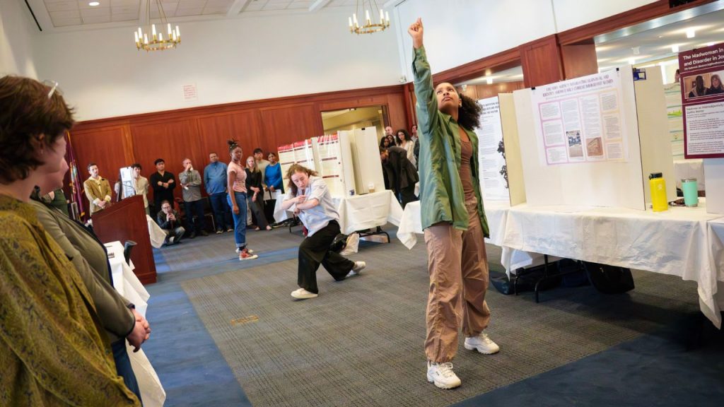 A group of dancers perform in a large conference room while bystanders look on