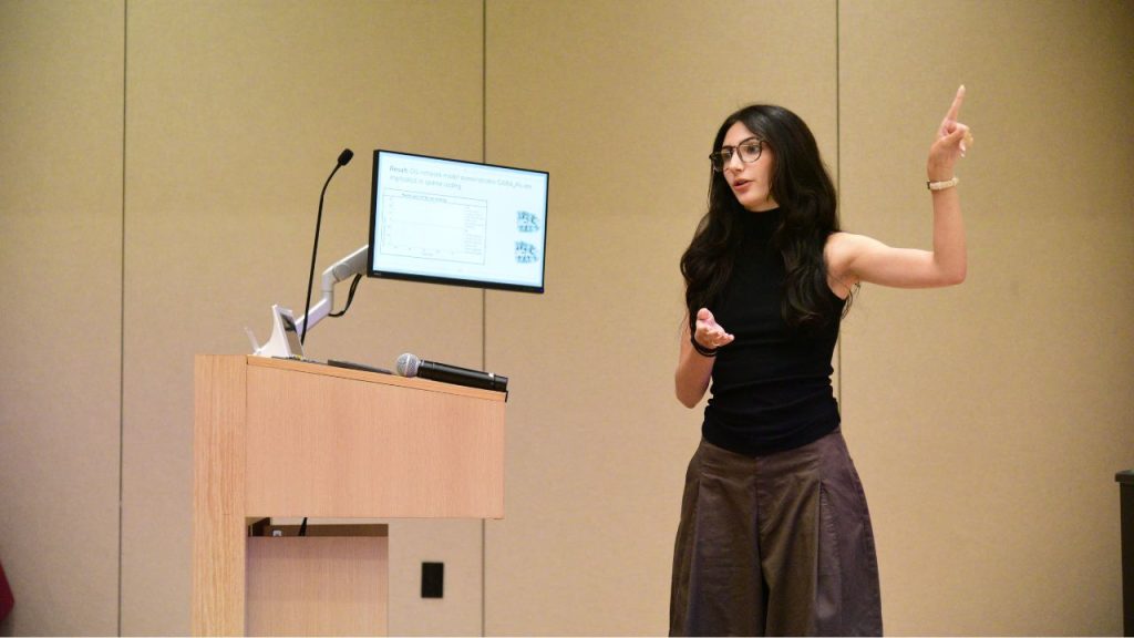 A young woman stands at a podium and gestures
