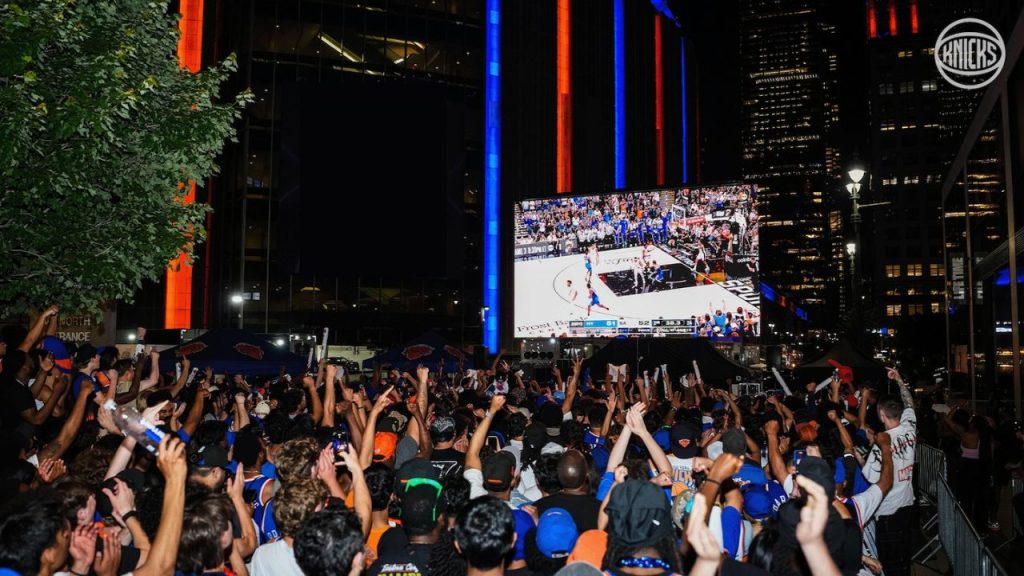A crowd watches a Knicks game on a screen outside of Madison Square Garden