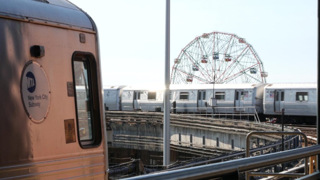 5 Things to Do in New York City | July 2026 A photo of an MTA train cruising pass the Wonder Wheel at Coney Island