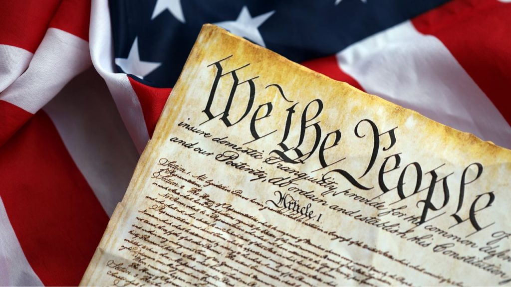 Is the Constitution Built for the 21st Century? An image of the preamble of the constitution in front of an American flag