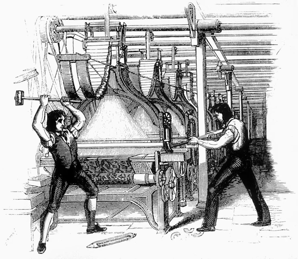 Black-and-white engraving depicts two 19th-century textile workers using large hammers to destroy a power loom inside a factory.
