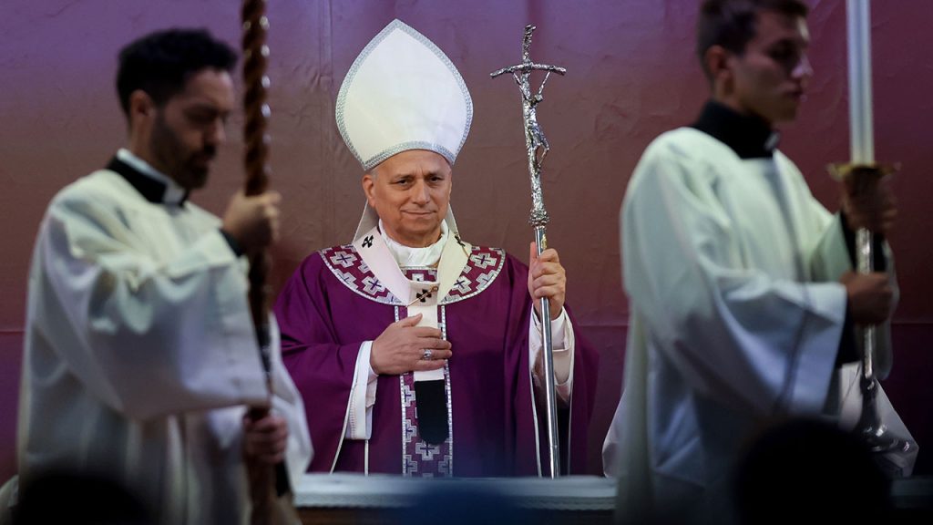 Pope Leo XIV wearing purple liturgical vestments and a white zucchetto, holding a silver papal ferula with crucifix, alongside altar servers.