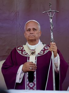 Pope Leo XIV wearing purple liturgical vestments and a white zucchetto, holding a silver papal ferula with crucifix.
