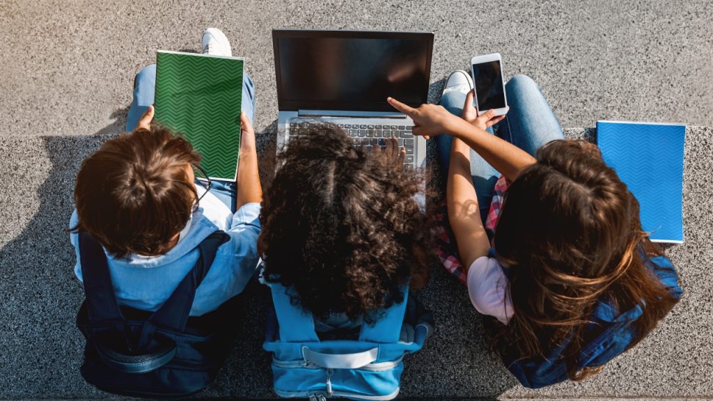 Three kids sitting in front of a laptop representing a landmark Meta trial for social media addiction