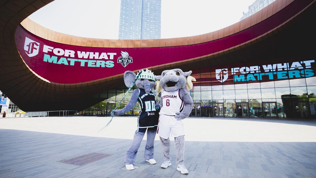 A photo of an elephant mascot and a ram mascot in front of Fordham branding at the Barclays center representing Fordham's partnership with the New York Liberty