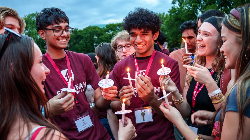 Students smile and hold candles.