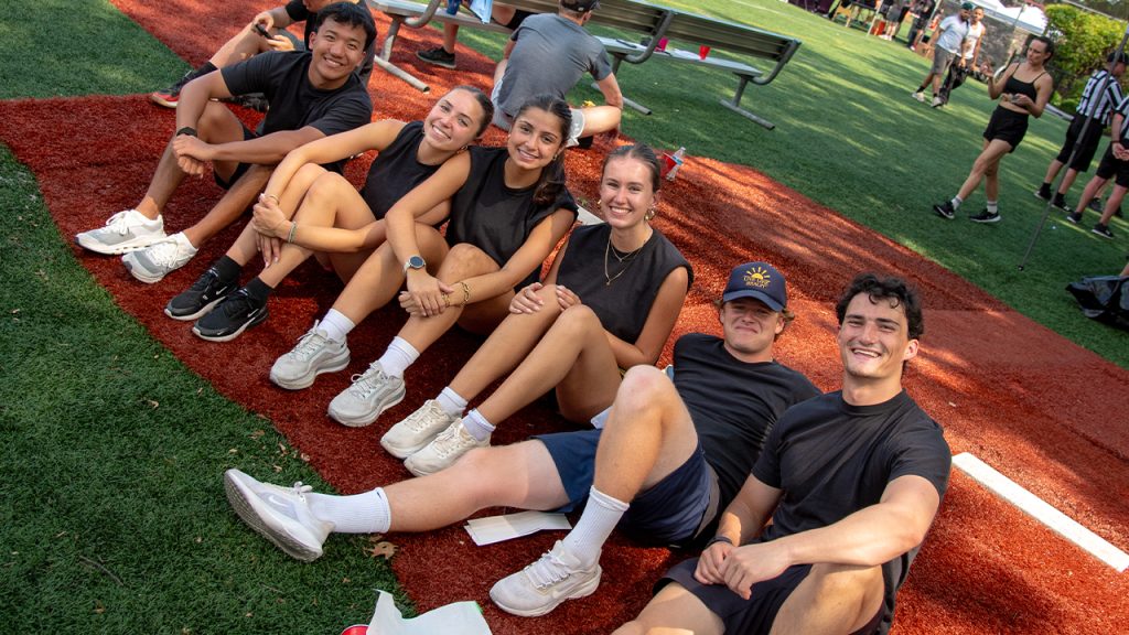 A group sits on the field posing and smiling