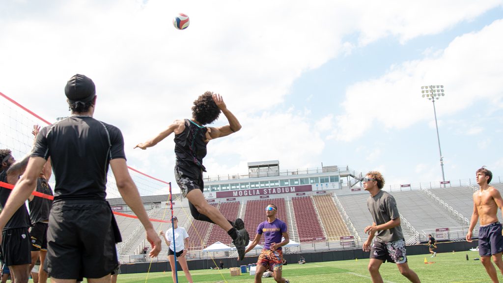 Photos: Former Athletes ‘Run It Back’ at Rose Hill A player jumping up preparing to hit a volleyball over the net.