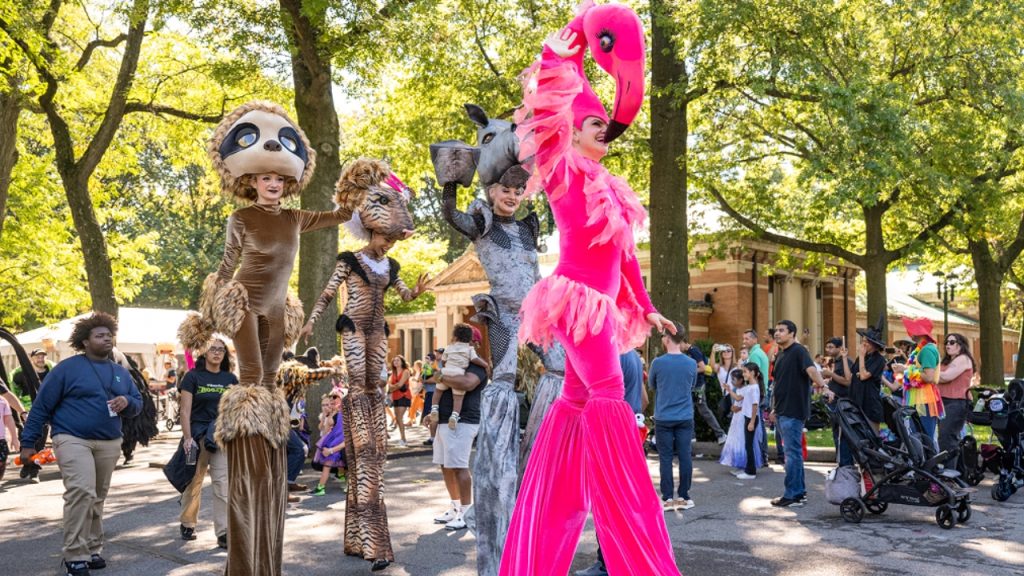 A group of people on stilts wearing animal costumes at the Bronx Zoo's Halloween Parade.