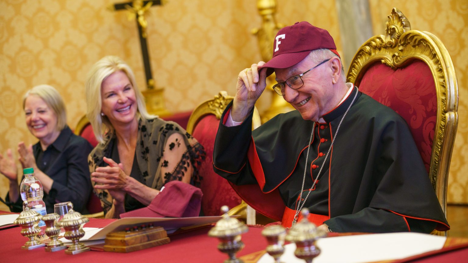 Cardinal Parolin puts on a Fordham baseball cap.