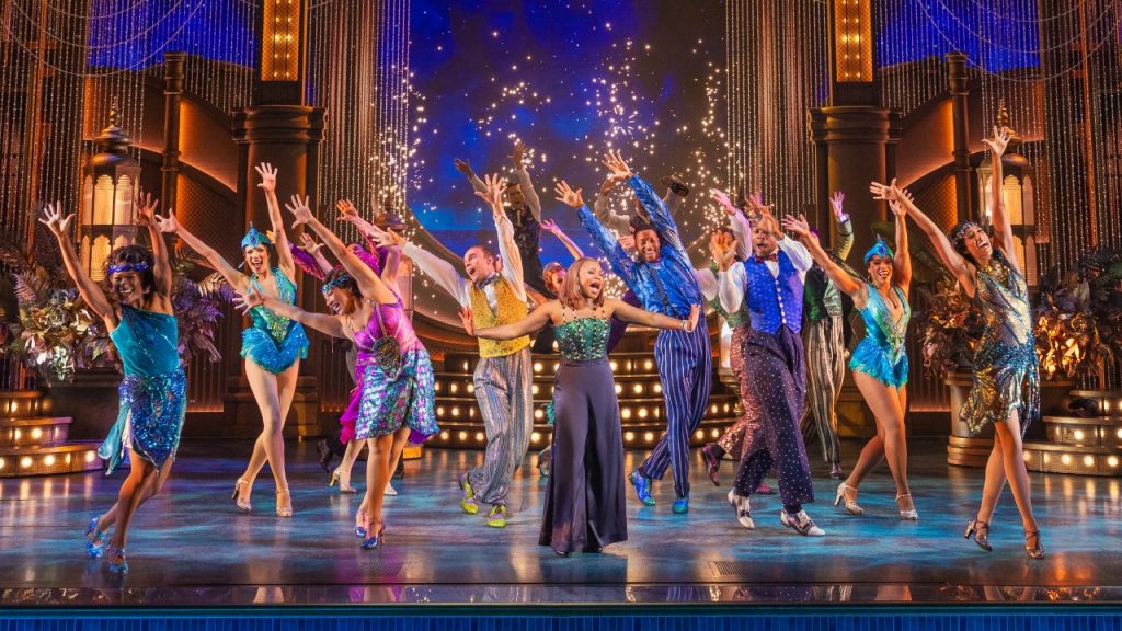 A group of dancers on stage with a singer in the center at a performance of "The Great Gatsby" on Broadway.