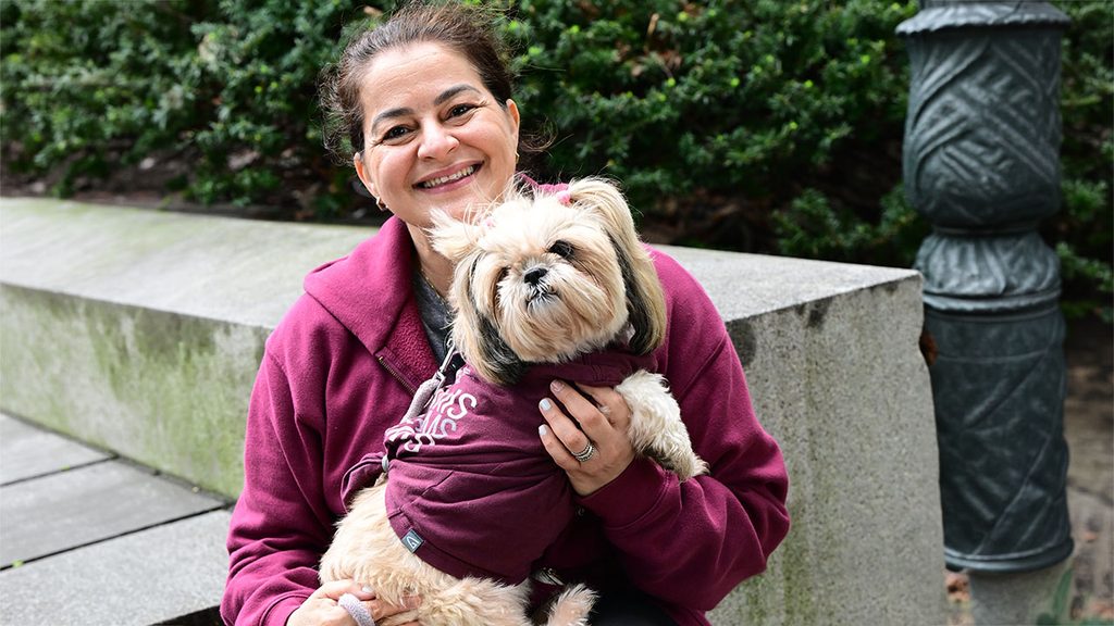 woman holding her dog who is wearing a sweater