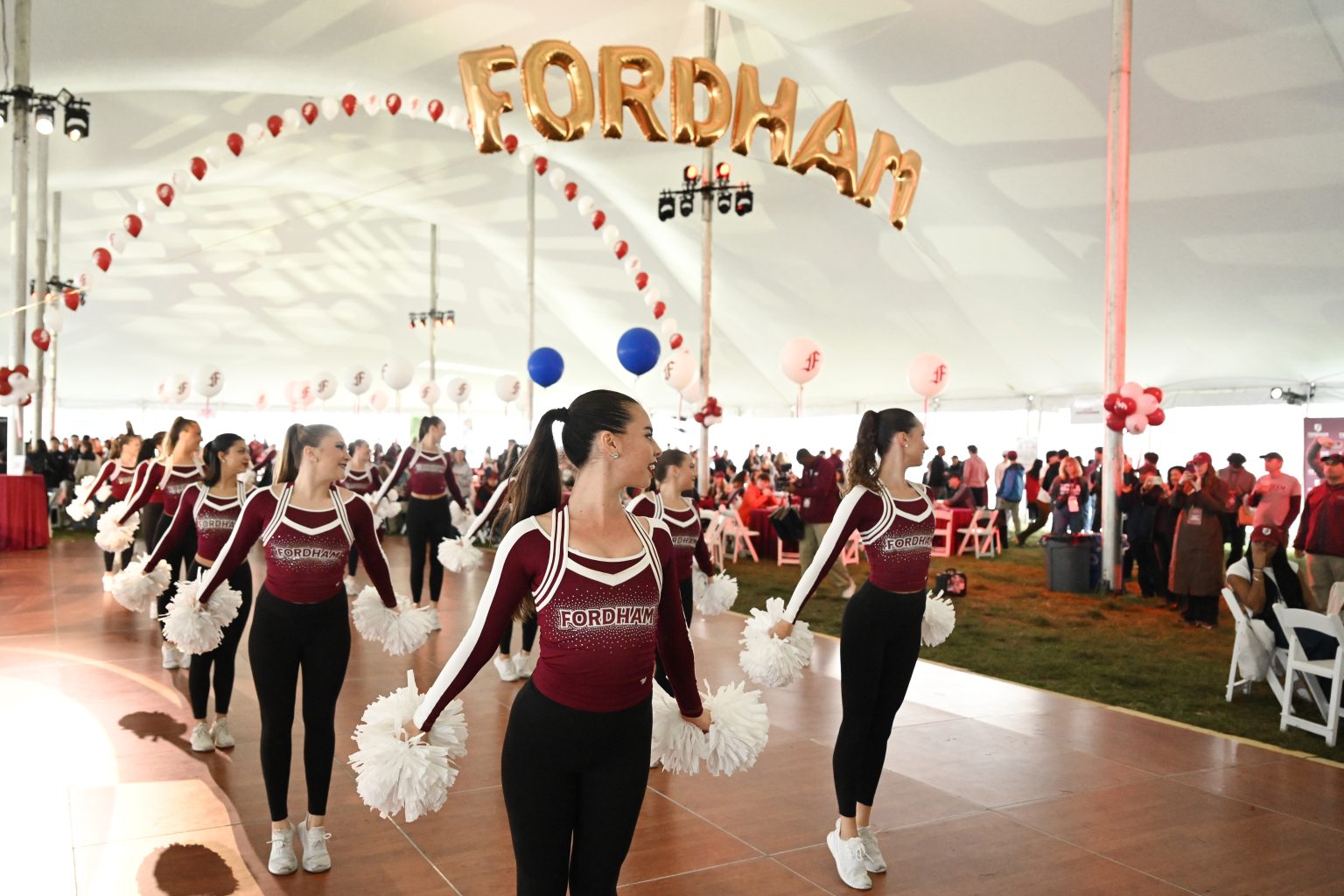 Fordham dance team performing in Homecoming tent under balloons