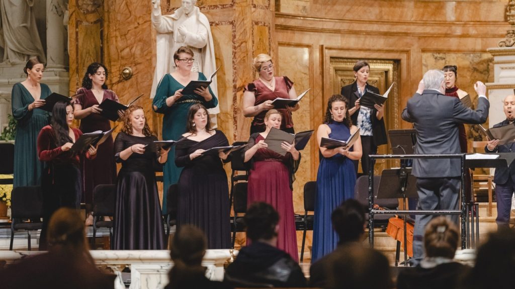 A group of people wearing formal wear singing in a choir inside a church.