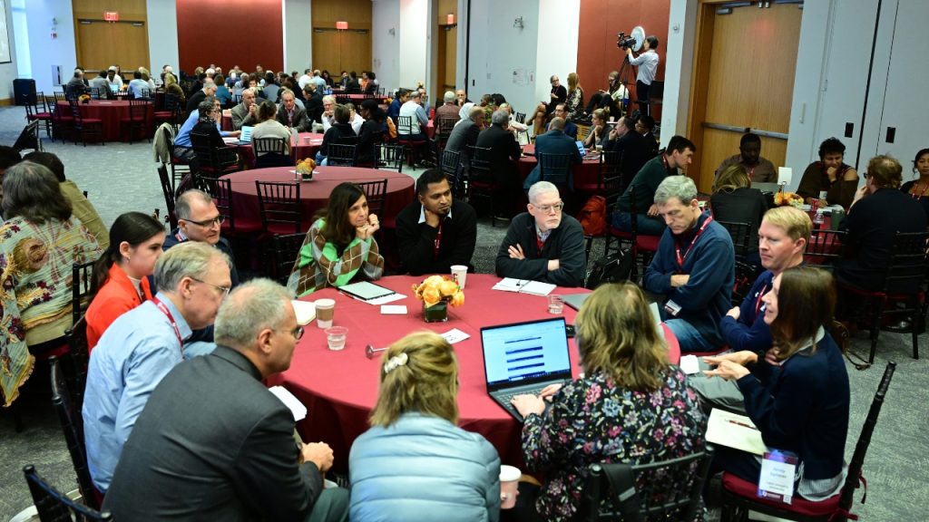A group of people sitting around tables at a conference conversing